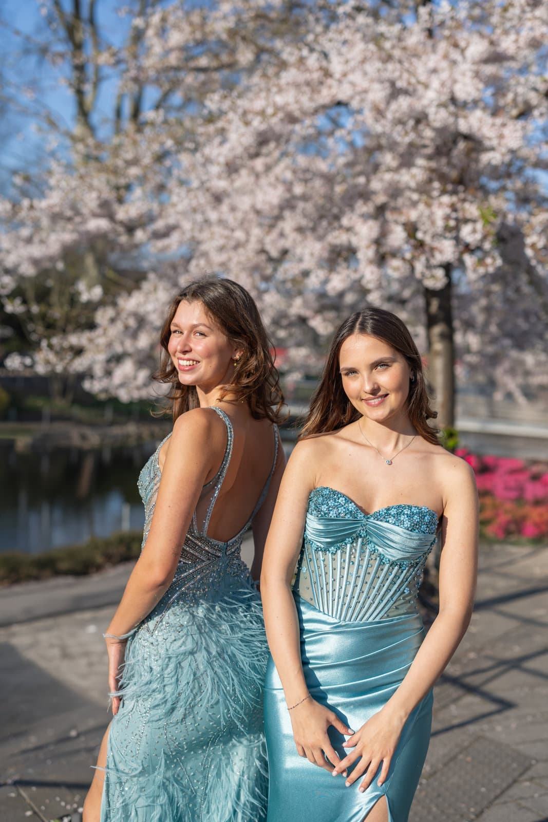 Zwei Frauen in türkisen Pailletten-Abendkleidern vor Kirschblüten